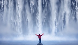 Person standing in front of huge waterfall